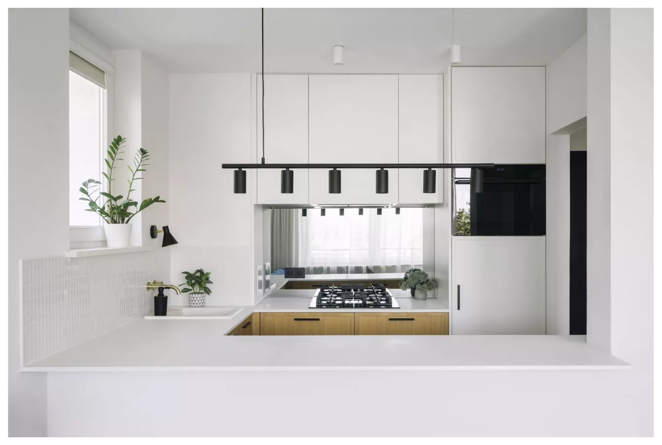 cocina minimalista con muebles blancos, detalles en madera y encimera de gas 